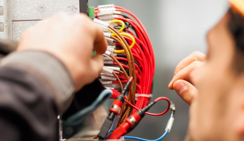 Electrician engineer tests electrical installations and wires on relay protection system