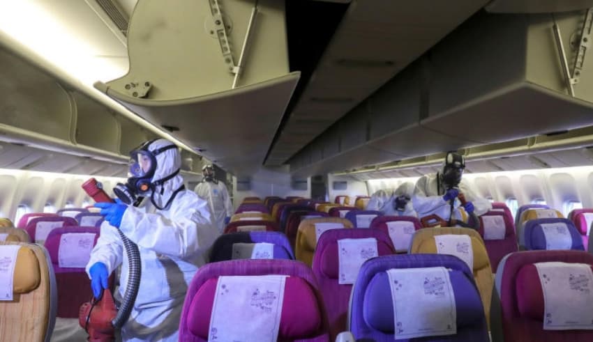 Members of a Thai Airways crew disinfect the cabin of an aircraft