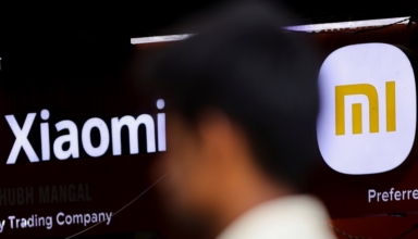 a man walks past a logo of xiaomi, a chinese manufacturer of consumer electronics, outside a shop in mumbai