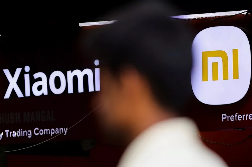 a man walks past a logo of xiaomi, a chinese manufacturer of consumer electronics, outside a shop in mumbai